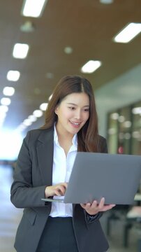 Asian businesswoman working at desk using laptop and notebook talking to client or office building, slow motion footage