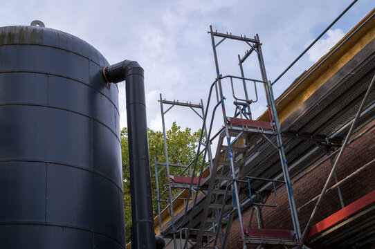 Construction work on a building showing scaffolding and large storage tanks near a construction site in the afternoon