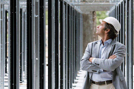Male engineer data center construction inspection hard hat server rack technology infrastructure industrial safety focused male engineer surveys modern data center construction site, inspecting