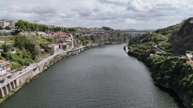 Douro river panorama in Porto Portugal with Infante Dom Henrique Bridge and lush hillsides under a cloudy sky aerial view cityscape drone