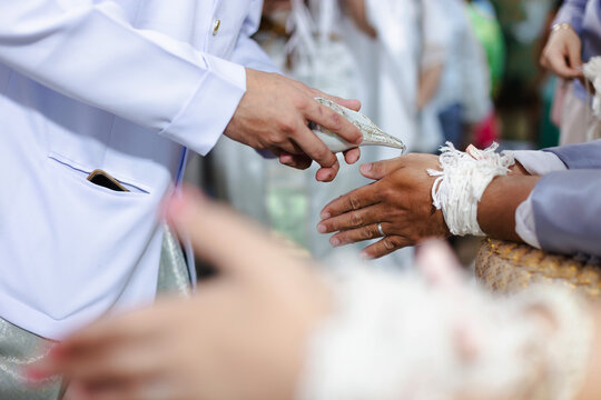 Groom Performing Traditional Water Blessing for Elder During Thai Wedding Ceremony