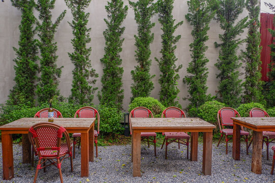 Luxury chair and wooden table set in english garden on a sunny day,outdoor seating for restaurant or cafe,Near paver patio with sitting area and small garden in forest.