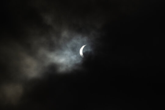 Iceland - 12 August 2026: View of a partial solar eclipse visible through dark, moody clouds over the Westfjords Region.