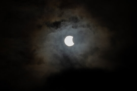 Iceland - 12 August 2026: View of a partial solar eclipse partially obscured by dark, dramatic clouds in the sky over the Westfjords Region.