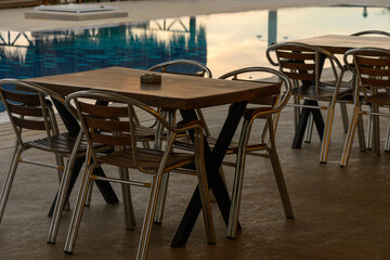 Fototapeta premium Charming outdoor dining setup by a tranquil swimming pool in the evening glow