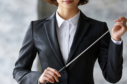 Businesswoman baton leadership authority power confidence suit conductor baton detail focus modern office background professional style gesture poised expression