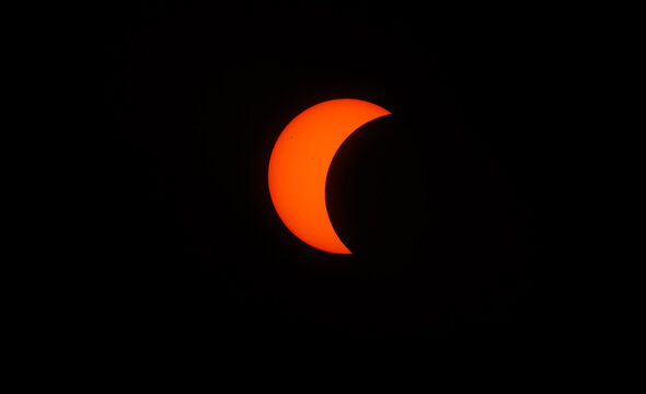 Spain - 12 August 2026: View of a partial solar eclipse with the moon obscuring a portion of the sun against a dark sky.