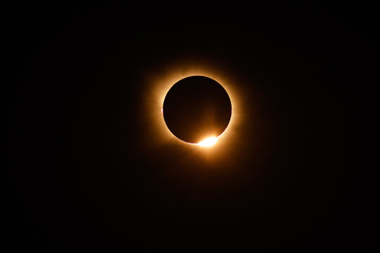 Spain - 12 August 2026: View of a total solar eclipse with the sun's corona visible and a bright flare of light emerging from behind the moon.