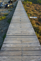 Obraz premium Sturdy wooden walkway leads through serene landscape at sunset, inviting exploration and tranquility
