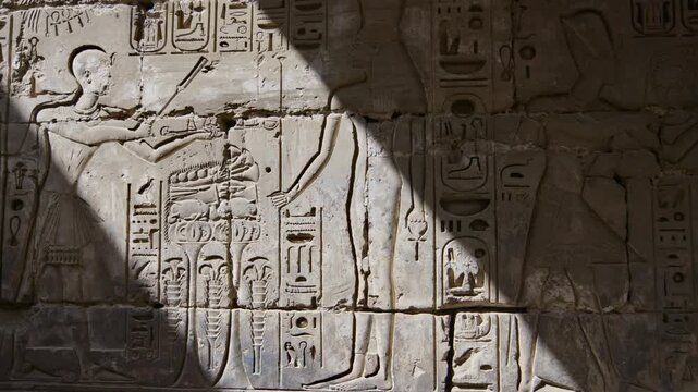 Karnak Temple in Luxor, Egypt. Close-up ancient Egyptian wall relief with pharaoh and gods figures, cartouche and hieroglyphics at Karnak Temple Luxor. Authentic history and documentary.