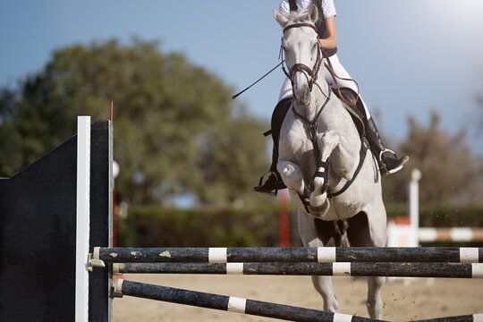 Jockey on her horse leaping over a hurdle, jumping over hurdle on competition