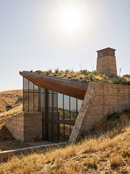 Earth sheltered home with cooling roof and natural landscape under bright sunlight