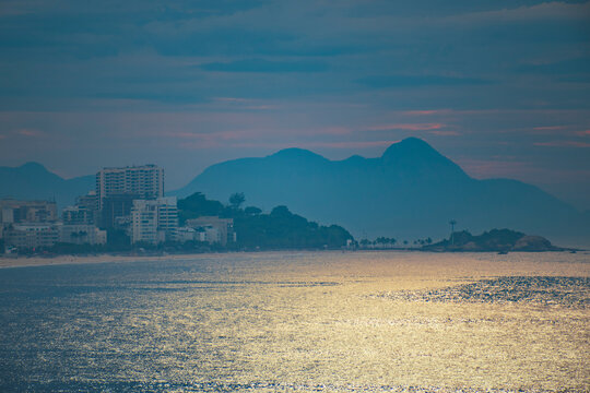 Coastal sunset in Rio de Janeiro with golden sea reflection and mountains