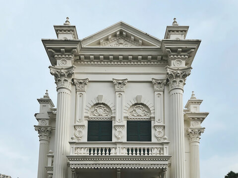 Architectural facade with corinthian columns and decorative pediment details against a bright sky