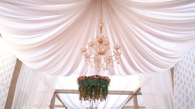 A luxurious wedding or event ceiling adorned with flowing, draped white satin fabric, creating soft, elegant swags across the frame