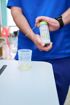 In the foreground is a container with a urine sample, and in the background, a veterinarian is holding a bottle of urine test strips