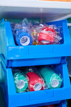 Blue medical storage boxes filled with elastic cohesive bandages in various sizes and colors