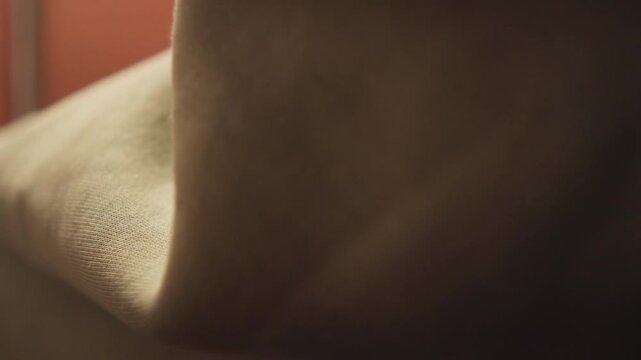 Close-up shows hands squeezing saturated coarse black sponge over dark sink beside stainless faucet in warm kitchen setting, with visible water streams, droplets, textured surfaces, and gentle