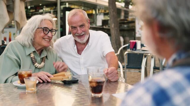Senior couple talking and laughing with a friend at a cafe
