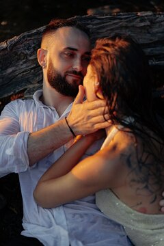Romantic couple embracing during sunset lying near dry log