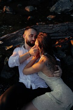 Romantic couple embracing during sunset lying near dry log