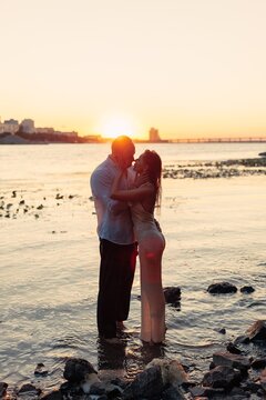 Full length passionate couple embracing in water about to kiss at sunset, young man and woman on river shore