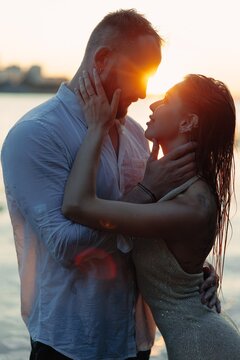 Romantic couple embracing at sunset, young lovers touching faces tenderly in golden sunlight