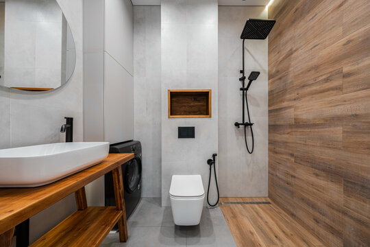 Wall-mounted toilet beside walk-in shower and timber-textured panels