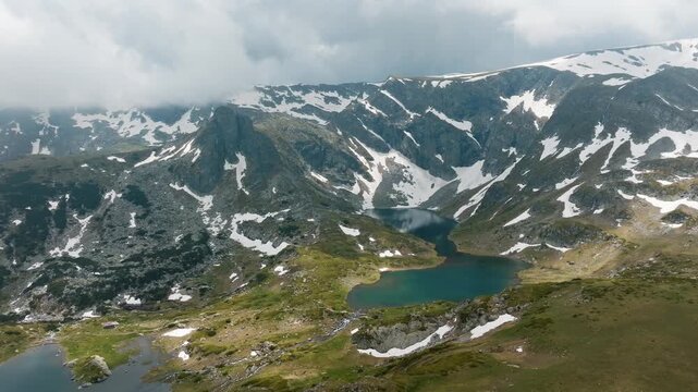 Seven Rila Lakes aerial drone view glacial mountain lakes snow patches cloudy sky Rila national park hiking trail wilderness summer landscape travel Bulgaria