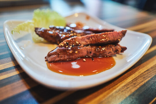 Sliced beef tataki with teriyaki glaze and sesame seeds