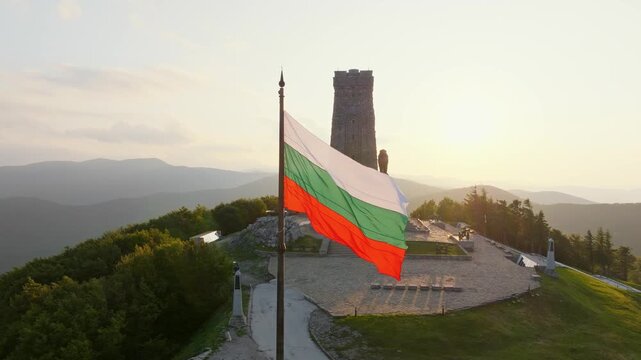 Shipka Freedom Monument close up aerial drone view Bulgarian national flag front golden sunset light peak Balkan mountains history landmark travel Bulgaria