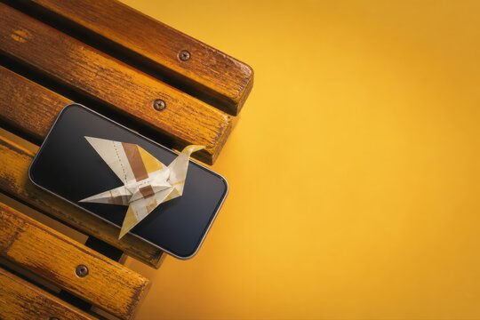 Paper Crane on Smartphone with Yellow Copy Space Background