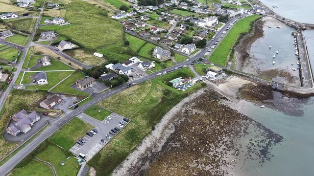 Scenic aerial drone footage of coastal Irish village of Mullaghmore, County Sligo, Ireland, showcasing stone pier with numerous sailing boats moored along the stone breakwater, picturesque nature