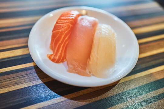 Three sashimi slices on a round plate from above