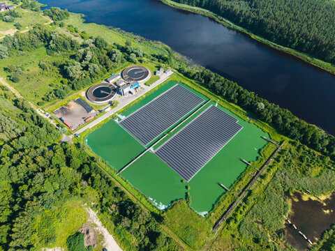 Aerial view of the floating solar power plant at the Sloka wastewater treatment plant, with circular sedimentation tanks and green water ponds in Jurmala, Latvia.