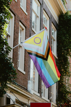 Pride flag waving on a building in an urban setting