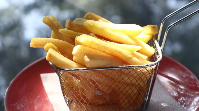 A basket of crispy French fries served on a vibrant red plate, perfect for a casual snack or meal