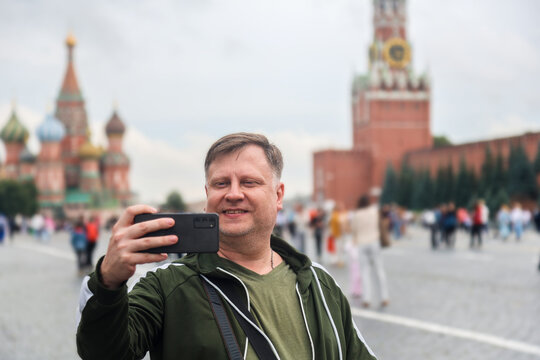 A blonde tourist stands in Red Square in Moscow, enjoying sightseeing near famous monuments and historical buildings.