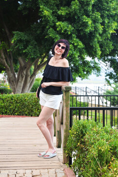 Portrait of attractive 40 year old brunette woman enjoying beautiful summer atmosphere outdoors smiling happily on warm sunny day.