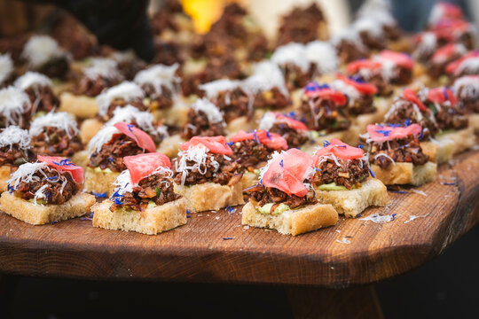 Cormorant breast tartare served as bite-sized canap&eacute;s on bread on Kihnu Island, Estonia, topped with grated garnish, pickled radis and edible flowers, presenting an unconventional wild food creation.