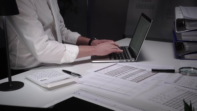 Dedicated finance professional at a cluttered desk, focused on analyzing documents and numbers with laptop, calculator and magnifying glass while managing company records and budgets