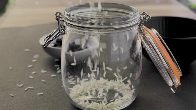 White basmati rice grains pouring into glass jar macro shot, FHD