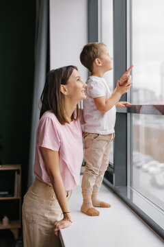 Smiling Mother with Toddler Son Pointing at Something through Window