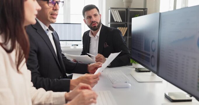 Analysts colleagues show teamwork in office meeting. They review finance data on computer dashboard, analytics charts, and discuss reporting and investment. Concept of data driven teamwork.
