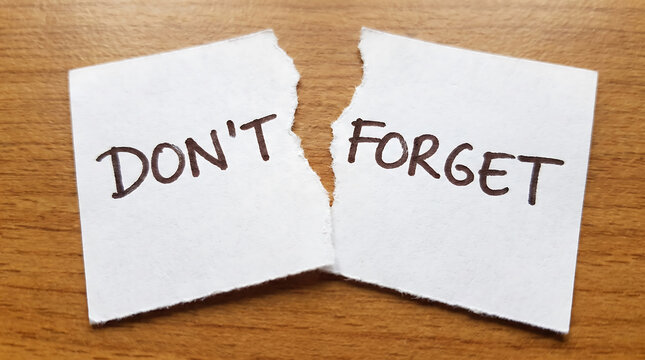 Torn paper note with handwritten text dont forget on wooden desk