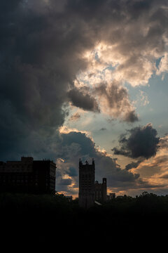 Dramatic twilight cloudscape, skyline with buildings, and forest in silhouette