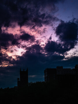 Dramatic twilight cloudscape, skyline with buildings, and forest in silhouette