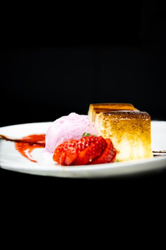 Cheesecake slice with strawberry slices, raspberry ice cream, and berry jam swirls