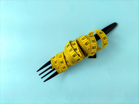 Conceptual image of dieting and weight loss featuring a measuring tape on a fork.