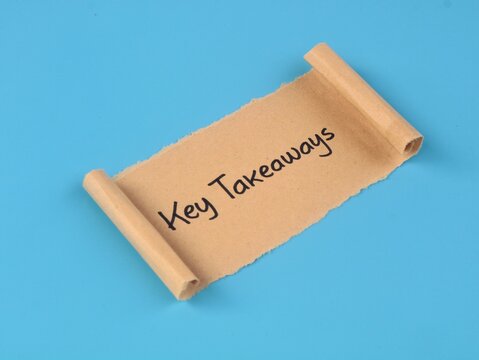 Top view of Key Takeaways handwritten text on a brown craft paper scroll over a blue background. Ideal for business summaries, educational content, presentation points, and learning concepts